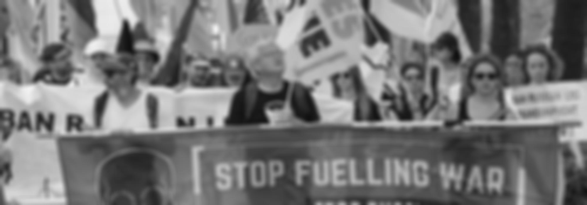 Een betoging met een banner waarop staat "stop fuelling war"