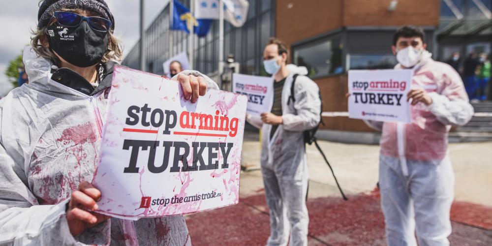 activisten voeren actie bij wapenbedrijf sabca - ze houden bordjes vast waarop "Stop Arming Turkey" staat