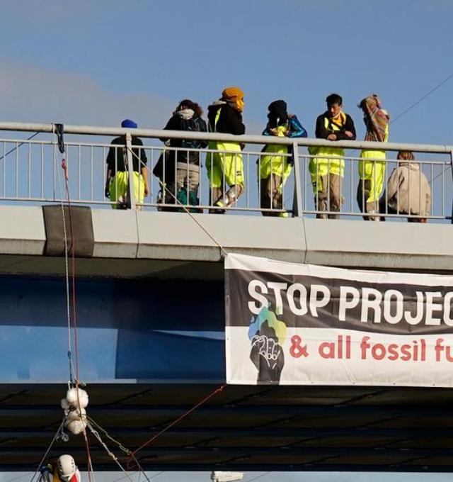 Activisten op een brug met spandoek 'stop project eacop & all fossil fuel projects'
